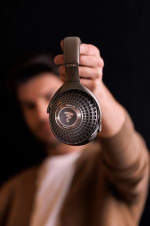 Person holding a pair of dark over-ear headphones toward the camera